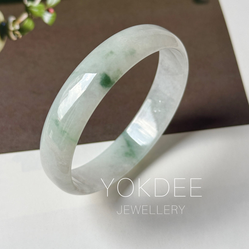 Floral jadeite bangle bangle displayed on a white surface with a dark brown background. The brand name 'YOKDEE JEWELLERY' is overlaid at the bottom.